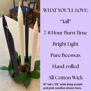 May include: Four hand-rolled beeswax taper candles in deep purple, cream, and light pink, featuring a textured honeycomb pattern and cotton wicks. The candles are 16 inches tall and 7/8 inches wide, displayed in a circular holder with green leaves.