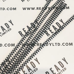May include: Multiple black metal coil binding spines for a notebook or planner. The coils are arranged in a row on a white surface with the text "READY LIMITED" printed on the surface.