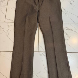 May include: A pair of brown straight-leg pants with a subtle texture. The pants have a zipper fly and belt loops.