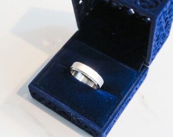 May include: A silver wedding band in a blue velvet ring box.