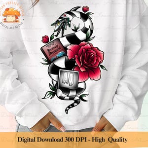 May include: White sweatshirt featuring a colorful graphic design. The design includes a black and white striped snake with a Beetlejuice-inspired character, a red rose, and a book titled "Handbook for the Recently Deceased".