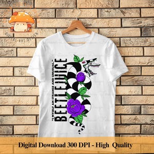 May include: White t-shirt with a black and white illustration of a creature with a purple flower. The text "Beetlejuice" and the quote "I myself am strange and unusual." are printed on the shirt.
