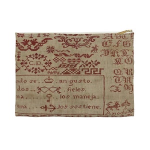 May include: A beige linen zippered pouch with a red embroidered design. The embroidery includes various symbols, letters, and the text "ndo se...un gusto. dos...fieles. na...los maneja. una...los sostiene."