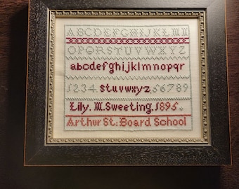 Pode incluir: Um sampler de ponto cruz emoldurado com o alfabeto, números e o texto "Lily M. Sweeting 1895 Arthur St. Board School".