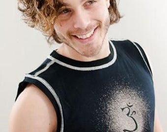 May include: A man with curly brown hair is wearing a black sleeveless shirt with a white trim. The shirt has a white symbol on the front.