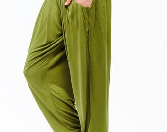 May include: Olive green yoga pants with a black elastic waistband and the word "yogamasti" printed on the waistband. The pants have a wide leg and a cuffed hem.