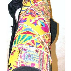 May include: A yellow yoga mat bag with colorful embroidered patchwork designs and a black adjustable strap.