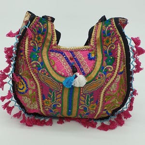 Puede incluir: Un bolso de mano rosa bordado con motivos florales coloridos y borlas. El bolso tiene una correa negra y un diseño único hecho a mano.