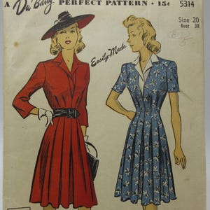 May include: Vintage sewing pattern featuring illustrations of two dresses. One is a red dress with a black belt and hat, the other is a blue dress with a white collar. The pattern is labeled "A De Barry PERFECT PATTERN".