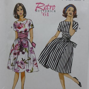 May include: Butterick sewing pattern B6318 featuring two retro dress designs. One dress has a floral print, the other has black and white stripes. The pattern includes the text "Retro '61".