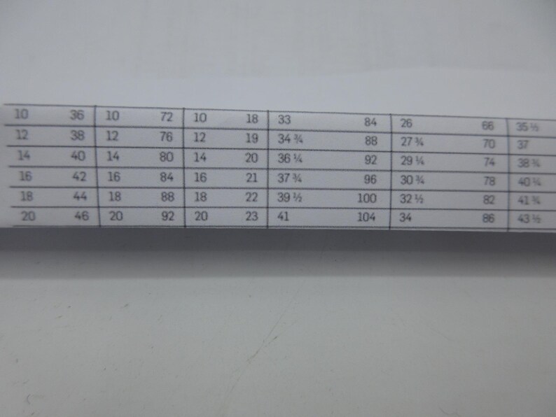 May include: A printed chart with rows and columns of numbers. The chart includes measurements, with values ranging from 10 to 104, and fractions. The chart is on a white background.