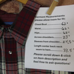 Puede incluir: Una camisa abotonada a cuadros burdeos, grises y blancos con cuello y cierre a presi&oacute;n. Las medidas de la prenda se enumeran en un papel adjunto con una pinza. Las medidas incluyen pecho, cintura, caderas, hombros, largo de manga y espalda.