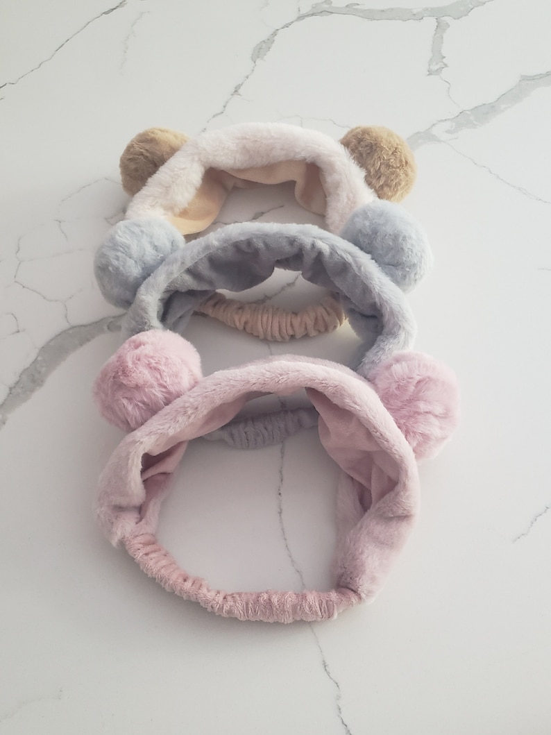 May include: Three fuzzy headbands with bear ears. The headbands are pink, gray, and beige.