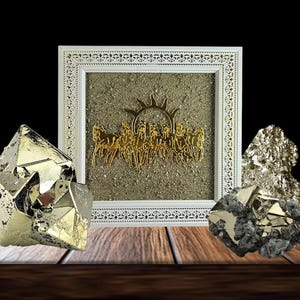 以下が含まれることがあります： 金色の戦車と馬のデザインが施された額入りのアートワーク。テクスチャード加工の背景。白いフレームには装飾的なボーダーがあります。黄鉄鉱の鉱物標本が木製の表面に配置されています。