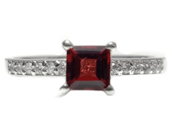 May include: A silver ring with a square red gemstone and a band of small clear gemstones.