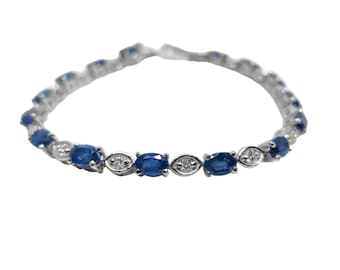 May include: A silver bracelet with oval-shaped blue gemstones and smaller clear gemstones.
