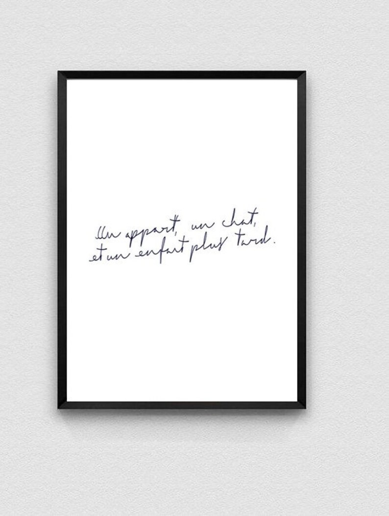 May include: A black framed print with a white background and a handwritten quote in French: "Il appartient un chat, et un enfant plus tard."