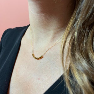 May include: A gold necklace with a row of small, round beads.
