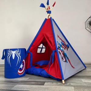 Puede incluir: Una tienda tipi roja y gris con ribetes azules y un contenedor de almacenamiento azul a juego. La tienda presenta ilustraciones del Capitán América y Spider-Man. El contenedor tiene un logotipo de Spider-Man y el escudo del Capitán América.