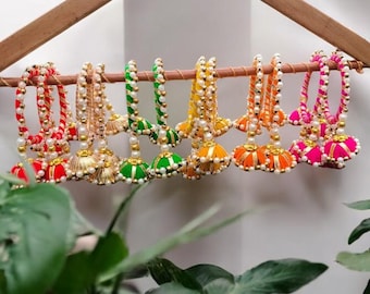 Può includere: Una collezione di frange di filo di seta colorate appese a un appendiabiti di legno. Le frange sono realizzate in filo di seta rosso, arancione, giallo, verde e rosa e hanno dettagli dorati.