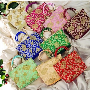 May include: Assortment of colorful embroidered handbags with gold accents. Each bag features a floral design with intricate details. The bags have a top handle and are made of a soft fabric.