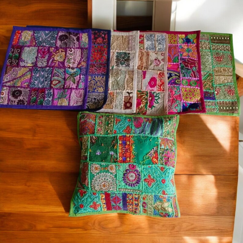 May include: Assortment of colorful patchwork throw pillows with intricate embroidery. The pillows are made of various fabrics and feature a variety of patterns and colors, including green, purple, pink, and brown.