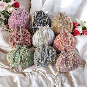 May include: Assortment of nine drawstring bags with pearl embellishments. The bags are made of a woven fabric and come in a variety of colors, including pink, red, green, blue, and white.