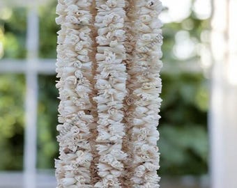 May include: A white garland made of small, delicate flowers. The garland is hanging from a ceiling and is made of multiple strands of flowers.