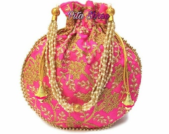 May include: A pink fabric drawstring bag with gold embroidery and pearl accents. The bag has a round shape and a drawstring closure. The bag is decorated with a floral pattern and has a gold tassel.