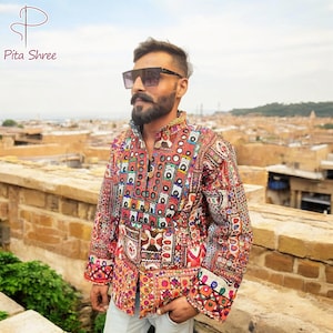May include: A colourful, patchwork jacket with intricate embroidery and embellishments. The jacket has a mandarin collar and a button closure. The person wearing the jacket is wearing sunglasses and has a beard.