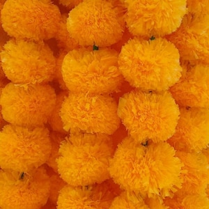 K&ouml;nnte beinhalten: Nahaufnahme einer Girlande aus leuchtend gelben Ringelblumen. Die Bl&uuml;ten sind aus Stoff und in einem kreisf&ouml;rmigen Muster angeordnet.