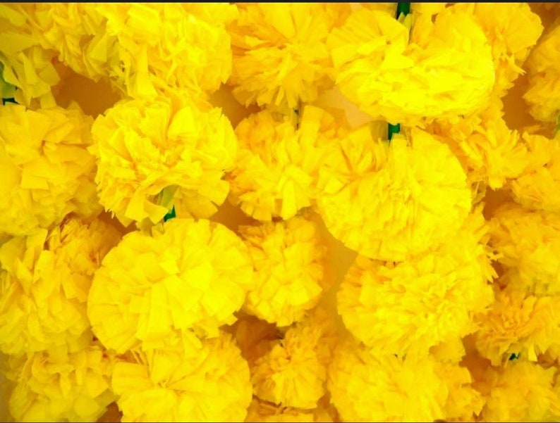 K&ouml;nnte beinhalten: Eine Girlande aus leuchtend gelben k&uuml;nstlichen Ringelblumen. Die Bl&uuml;ten sind aus Papier und zu einer Schnur zusammengef&uuml;gt.