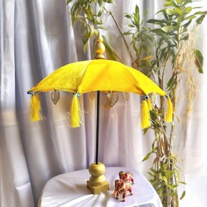 May include: A yellow velvet umbrella with gold accents and tassels. The umbrella is on a stand with a gold base.