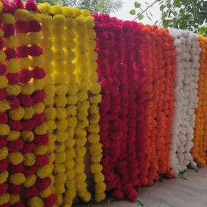 K&ouml;nnte beinhalten: Eine Girlande aus gelben und rosa Ringelblumen, eine beliebte Dekoration f&uuml;r indische Hochzeiten und Feste.
