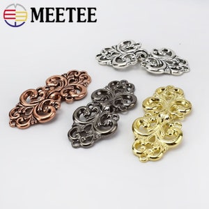 May include: Four ornate metal clasps in gold, silver, copper, and black.