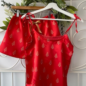May include: Red satin pajama top and shorts set with a gold Christmas tree print.