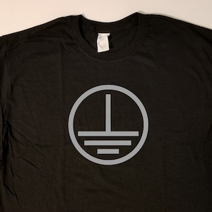 May include: Black t-shirt with a gray circle graphic featuring a vertical line and three horizontal lines.
