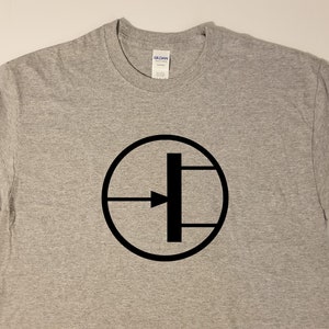 May include: A gray t-shirt with a black circle containing a stylized transistor symbol.