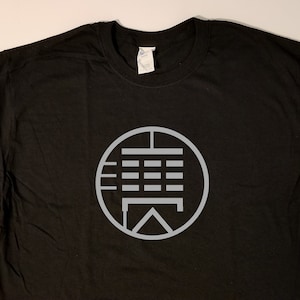 May include: Black t-shirt with a gray circle graphic featuring a stylized design of a table with a grid pattern.