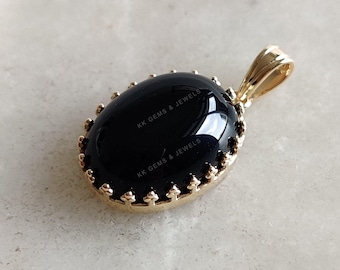 May include: A black onyx pendant with a gold-tone setting. The pendant features a detailed, ornate border and the text "KK Gems & Jewels" is engraved on the stone.