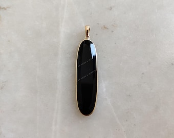 May include: A black oval pendant with a gold bail. The pendant is made of polished black onyx.