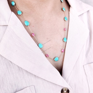 May include: A gold chain necklace with alternating turquoise and pink oval-shaped stones.