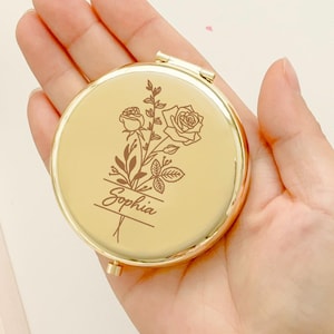 May include: Gold compact mirror with a floral design and the name "Sophia" engraved on it.
