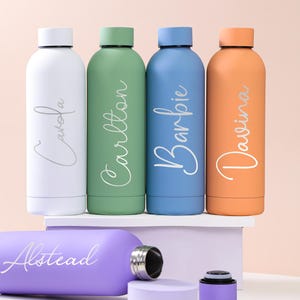 Puede incluir: Una colección de botellas de agua personalizadas en blanco, verde, azul y naranja, cada una con un nombre en fuente cursiva. Una botella morada con el nombre "Alstead" se muestra por separado. Las botellas tienen tapas plateadas.