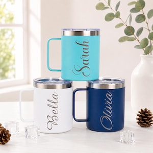 May include: Three insulated travel mugs in teal, white, and navy blue are stacked. Each mug has a silver rim, handle, and lid. The names "Sarah", "Bella", and "Olivia" are scripted on the mugs.
