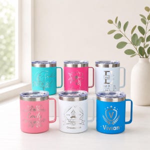 May include: Six personalized stainless steel travel mugs in various colors: teal, pink, white, and blue. Each mug features a silver design and a name or text, including floral and geometric patterns. The mugs have silver lids and handles.