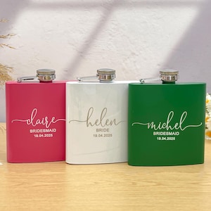 Könnte beinhalten: Drei personalisierte Flachmänner in Rosa, Weiß und Grün. Jeder Flachmann hat einen silbernen Deckel und ist mit einem Namen, einer Rolle und einem Datum in eleganter Schrift versehen. Der rosa Flachmann trägt die Aufschrift "claire, Brautjungfer, 19.04.2025". Der weiße Flachmann trägt die Aufschrift "helen, Braut, 19.04.2025". Der grüne Flachmann trägt die Aufschrift "michel, Brautjungfer, 19.04.2025".