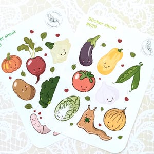 Könnte beinhalten: Zwei Stickerbögen mit Illustrationen von lächelndem Gemüse. Die Sticker zeigen einen Kürbis, eine Radieschen, eine Aubergine, einen Kürbis, eine Tomate, Knoblauch und mehr. Auf einem Bogen steht der Text "Sticker sheet #020".