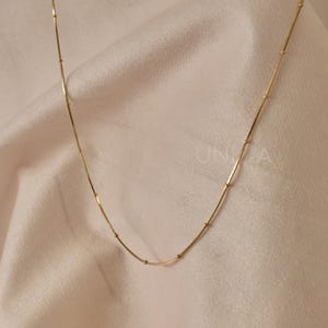 May include: A gold chain necklace with small round beads. The chain is delicate and has a simple design.