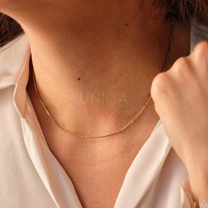 May include: A gold chain necklace with small round beads. The necklace is delicate and simple, perfect for everyday wear.